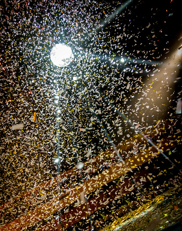 Lights show off a large amount of confetti at a music concert with lights on a mirror ball
