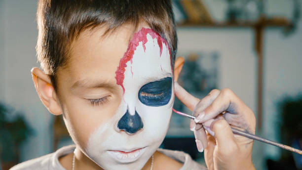 Make-up artist makes the boy halloween make up. Halloween child face art. Make-up artist makes the boy halloween make up. Halloween child face art. Drawing skull body art for halloween party. face paint halloween adult men stock pictures, royalty-free photos & images