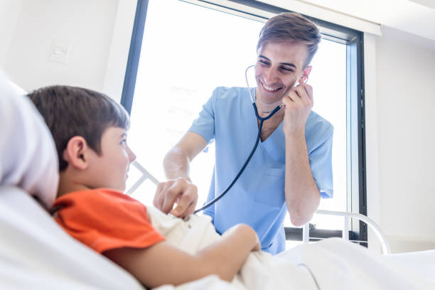 istock Friendly pediatrician checking his little patient with a stethoscope while patient is lying on hospital bed 1055957270