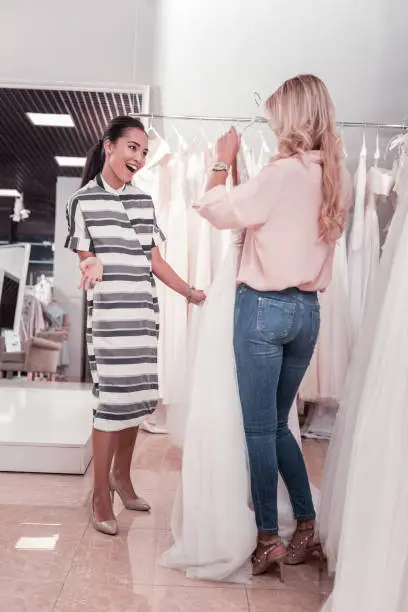 Photo of Positive happy women choosing a wedding dress together