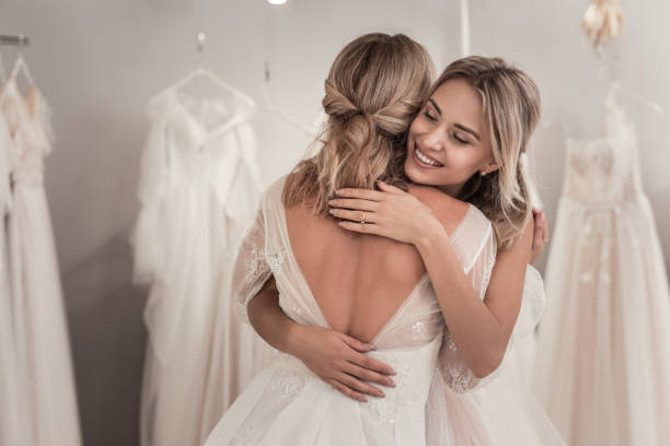 Nice happy woman hugging her best friend Like a sister. Nice happy woman hugging her best friend while standing in the wedding dress shop bridal shop photos stock pictures, royalty-free photos & images