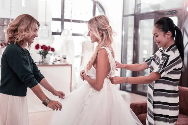 Photo of Joyful pleasant women standing around the bride