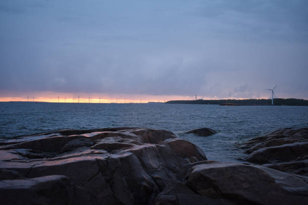 istock Sunset on a gloomy day, turbines and rocky shore 1055970234