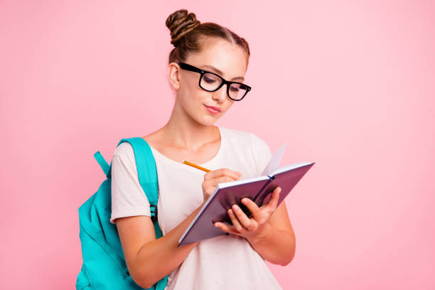 retrato de menina do estudante leitor concentrado escreve no caderno isolado no fundo rosa vívido, com espaço de cópia de texto - nerd student female exam - fotografias e filmes do acervo