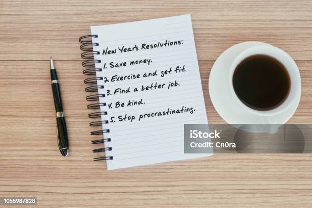 New Year Resolutions List On Notepad On Top Of Wood Desk Stock Photo - Download Image Now