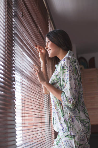 istock Woman in pajamas looking out the window 1055988748
