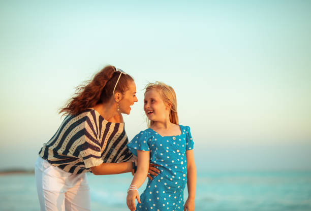 istock smiling mother and child on beach in evening having fun time 1055994050