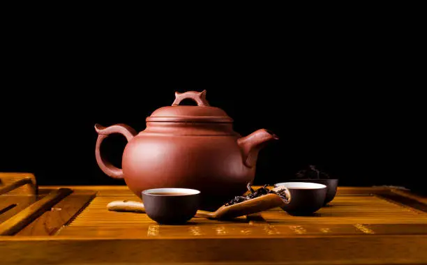 Chinese tea ceremony. Ceramic tea pot and cups with the famous chinese oolong tea Da hong pao on a wooden background.