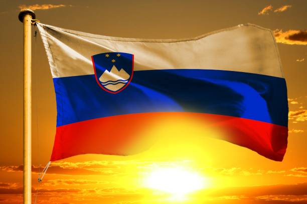 istock Slovenia flag weaving on the beautiful orange sunset with clouds background 1055998756
