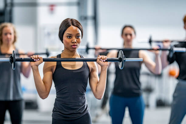 istock Strong young woman lifting weights with a group at the gym 1056000018
