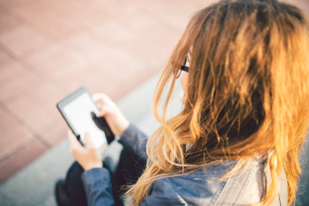 istock Girl sitting on the steps outdoor and using tablet. 1056003462