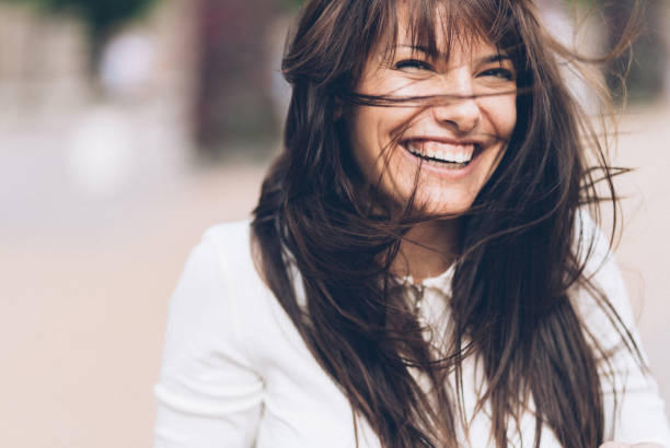 mujer sonriente en un día ventoso - cabello castaño fotografías e imágenes de stock