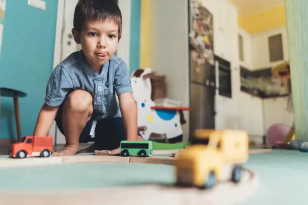 Photo of Cute little boy playing with wooden train