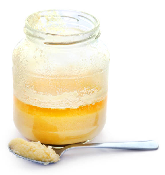 Ghee or clarified butter Ghee or clarified butter in a jar with spoon over white background clarified butter stock pictures, royalty-free photos & images