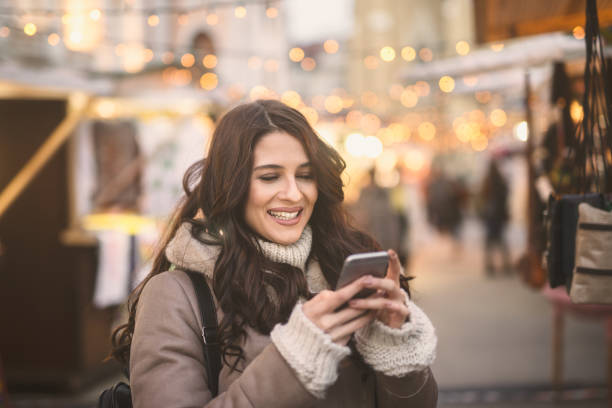 istock Happy Caucasian woman using smart phone for texting/reading message while standing on the street. 1056009396