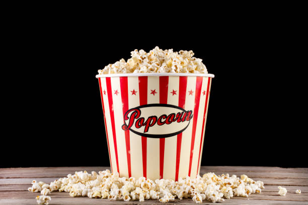 istock Full box with popcorn and spilled on retro wooden desk 1056018636