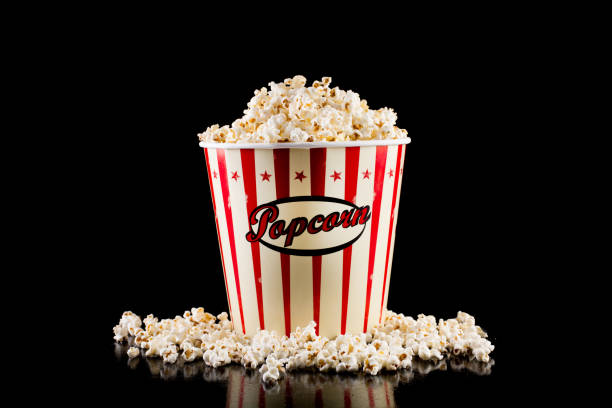 istock Retro popcorn box full and spilled popcorn isolated on black 1056018660