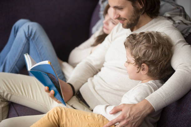istock Family sitting on couch at home with a book 1056019112