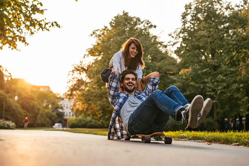 Shot of a smiling happy couple having fun skateboarding outdoors.