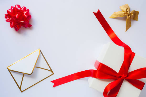 istock Envelope, golden bow and white gift box with red satin bow and ribbon on white background with copy space/christmas background concept 1056035734