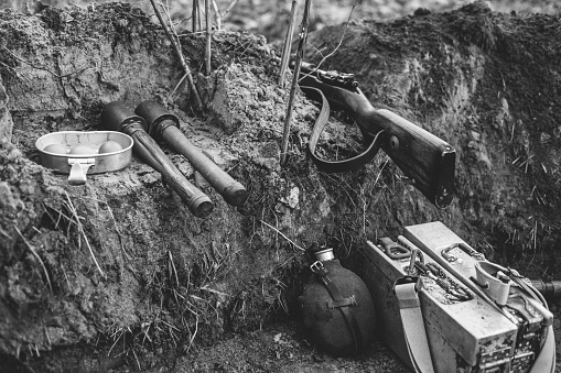 German Military Ammunition Of World War II On Ground. Rifle, Grenades, Flask. Photo In Black And White Colors.