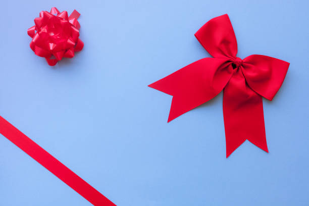 istock Red satin bow and ribbon on blue background with copy space/christmas card concept 1056037218