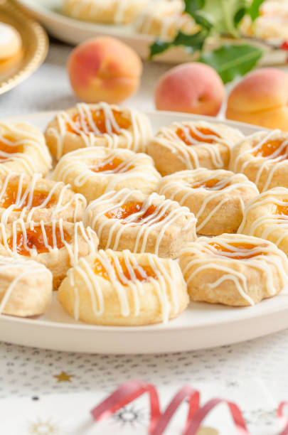 Czech Kolache Cookies Homemade cream cheese Kolache cookies filled with apricot and glazed in a plate and served on a festive table for a Christmas holiday menu kolache stock pictures, royalty-free photos & images
