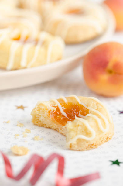 Czech Kolache Cookies Focus on a homemade cream cheese Kolache cookie filled with apricot and glazed in a plate and served on a festive table for a Christmas holiday menu kolache stock pictures, royalty-free photos & images