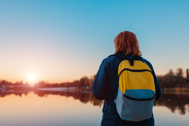 istock Tourist with backpack walking in autumn forest. Middle-aged woman travelling alone 1056055292