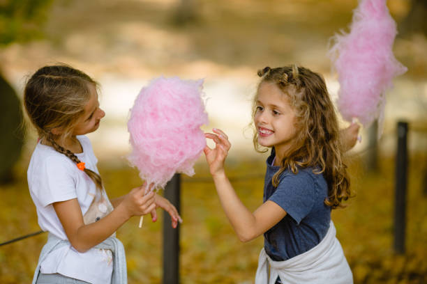 istock Two girls eating cotton candy in the park 1056067498