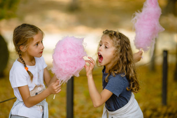 istock Two girls eating cotton candy in the park 1056068198