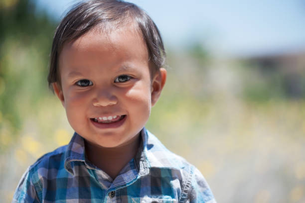Smiling boy 2 year old wearing plaid shirt outdoors on a sunny summer day looking healthy and happy stock photo