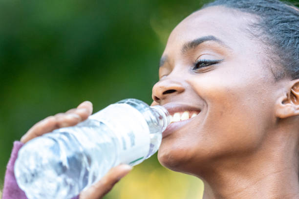 istock Smiling beautiful young black woman drinking bottled water 1056080084