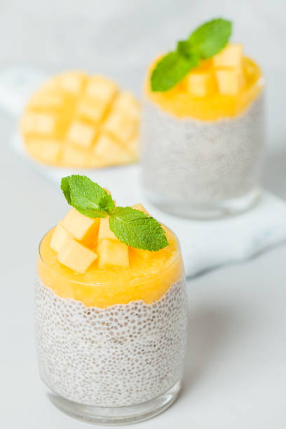 istock Chia seeds pudding with mango puree in beautiful glasses with green mint leaves and cut fresh ripe tropical fruit. 1056090246