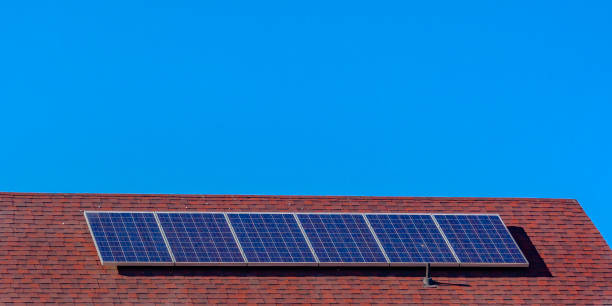 istock Solar panels on a red roof beneath clear blue sky 1056105310