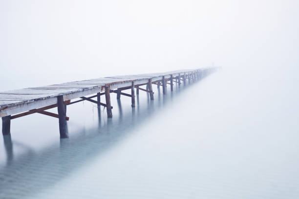 Foodbridge in the fog with a man standing on it Foodbridge in the fog with a man standing on it footbridge photos stock pictures, royalty-free photos & images