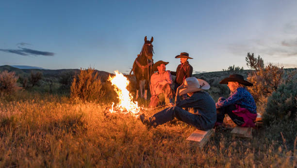 Farming family and friends gathered around a campfire at night while toasting marshmallows