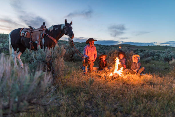 Farming family and friends gathered around a campfire at night while toasting marshmallows