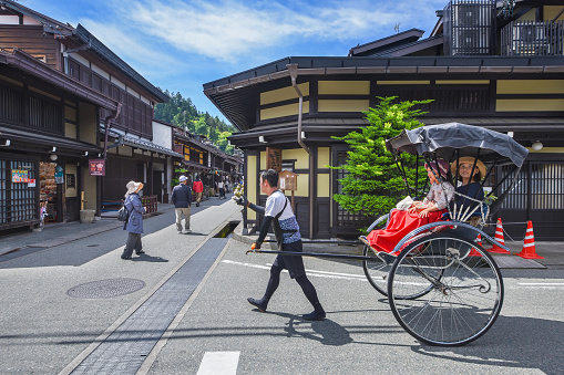 Takayama, Japan - 5 June 2017 : Jinrikisha or Japanese rickshaw driven by male driver carrying women tourist for sightseeing in historical city Takayama in Japan. This place is main travel attraction in Takayama
