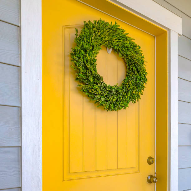 istock Yellow front door with ornamental green wreath 1056124438