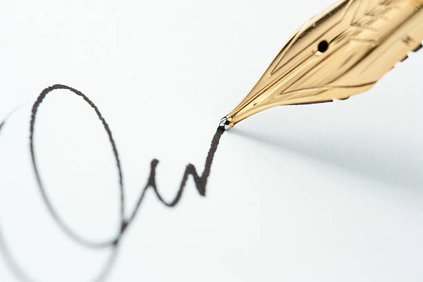 Close-up of a Caucasian female hand holding a fountain pen and writing a purchase contract in Czech language. Concept for old law, legal issues and old handwritten documents.