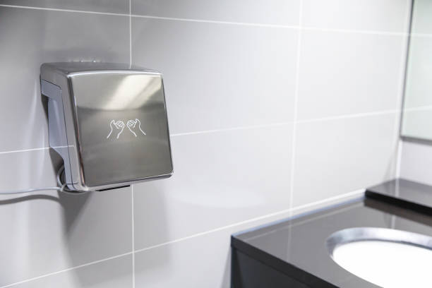 Automatic bathroom hand dryer in public WC toilet stock photo