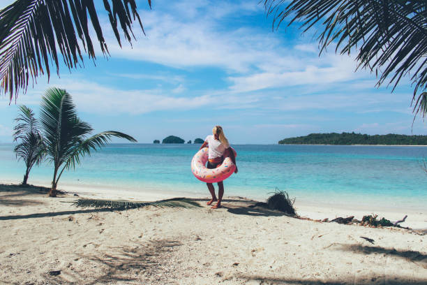 istock Women walking on the beach in bikinis with floaty 1056161694