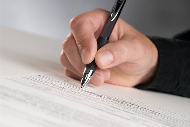 Man holding pen signing document man's hand holding a pen writing his signature pleading stock pictures, royalty-free photos & images