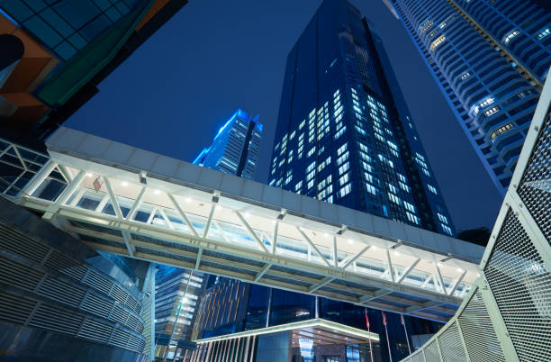 Low angle view of walkway bridge and skyscraper office building Low angle view of walkway bridge and skyscraper office building , night scene elevated walkway stock pictures, royalty-free photos & images