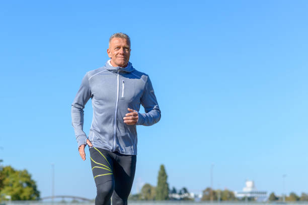 istock Gray smiling man running through a park 1056177140