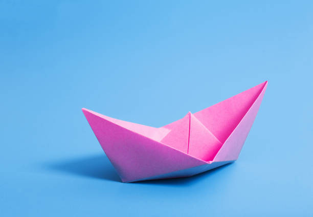 istock paper boat on blue paper background 1056181638