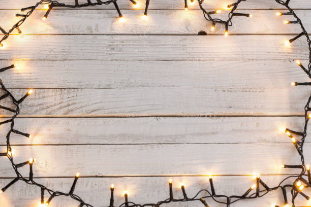 istock Christmas lights on white wooden background 1056181654