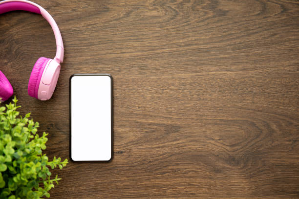 istock phone with isolated screen on wooden table with headphones 1056205162
