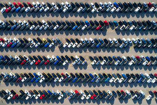 Aerial view of new cars of different brands parked in rows on a lot.